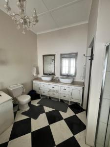 a bathroom with two sinks and a checkered floor at Toni's Cottage in Graaff-Reinet +27 photos