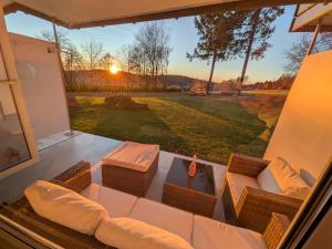 a screened in porch with a couch and a table at Green Wellness Pools Saunas Apartment with Alpine view Terrace in Sankt Englmar