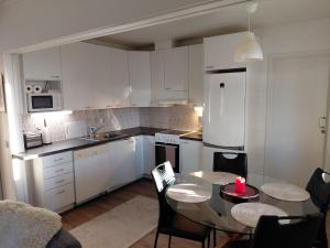 een keuken met witte kasten en een tafel en stoelen bij Viihtyisä huoneisto Ivalossa in Inari +4 foto's
