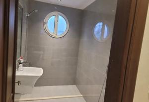 a bathroom with a sink and a shower with two windows at فيلا درة العروس in Dahaban +36 photos
