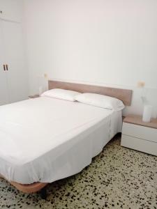a bed with white sheets and pillows in a room at Tamariua L2, apartamento cerca de la playa del Pas in Port de la Selva