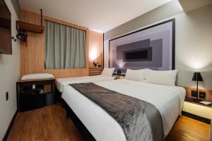 a hotel room with a large bed and a tv at ibis Navegantes Itajai in Itajaí