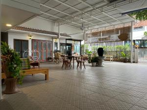 een patio met een tafel, stoelen, tafels en banken bij Baan Khunsri Guesthouse in Chiang Rai