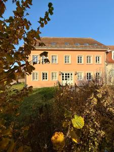 a large peach colored house with a roof at Schlösschen am Rhinufer in Alt Ruppin
