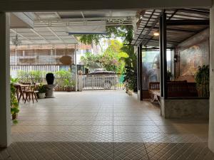 een lege patio met tafels, stoelen en planten bij Baan Khunsri Guesthouse in Chiang Rai