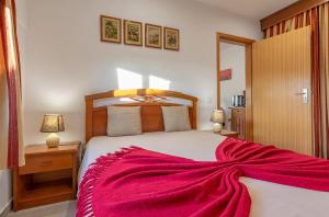 a bedroom with a large bed with a red blanket on it at Terrace Villa with Sea View in Santa Luzia