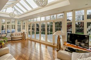 ein Wintergarten mit einem großen Wohnzimmer mit Fernseher und Glasfenstern in der Unterkunft Luxury Detached House in private grounds, with SPA in Weston upon Trent