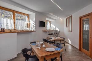 a dining room with two tables and chairs and windows at B&B Soreghina in Malè