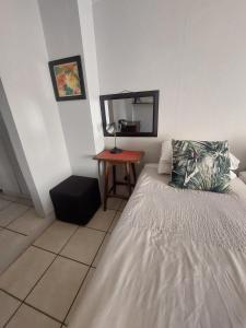 a small bedroom with a bed and a table at Turtle Creek - Ridleys in Umkomaas