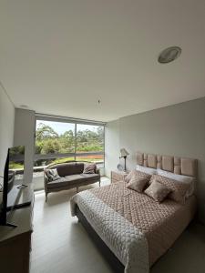une chambre avec un grand lit et une grande fenêtre dans l'établissement PORTANOVA SUITES - Apartamento muy cómodo, a tan sólo 5 minutos del aeropuerto JMC, à Rionegro
