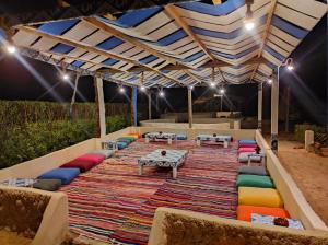 a large rug with colorful pillows and tables under a tent at Esewan siwa oasis in Siwa +33 photos