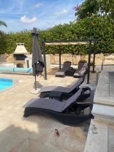een groep ligstoelen en een parasol naast een zwembad bij Villa Private Heated Pool Sea Views- Sleeps6 in Kouklia