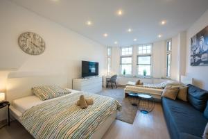 a living room with a bed and a couch and a clock at HagenStay Eilpe 1 in Hagen