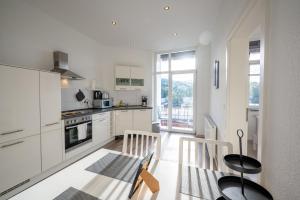 a kitchen with white cabinets and a table and chairs at HagenStay Eilpe 1 in Hagen