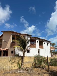 a building with a palm tree in front of it at Bela Vista in Canoa Quebrada