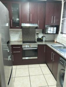 eine Küche mit braunen Schränken und einem Edelstahl-Gerät in der Unterkunft Whispering Waves SummerSands in Durban