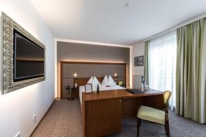 een hotelkamer met een bureau en een bed bij GORITSCHNIGGs Hotel - Self Check-In in Velden am Wörthersee