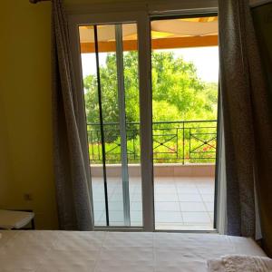 een slaapkamer met een glazen schuifdeur naar een balkon bij Villa Voula agios Ioannis Lefkada in Lefkada