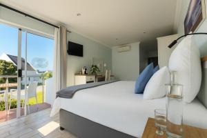 a bedroom with a large white bed and a balcony at BlueSky Arniston Guest House in Arniston
