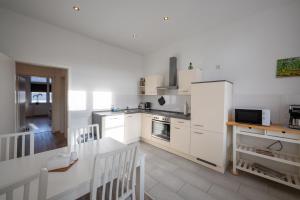 eine Küche mit weißen Geräten sowie einem Tisch und Stühlen in der Unterkunft HagenStay Eilpe 2 in Hagen