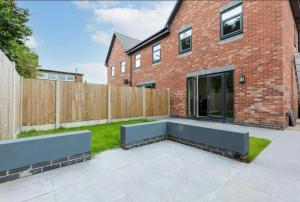 ein Hinterhof mit einer Bank vor einem Backsteingebäude in der Unterkunft Norris Stays - Sleeps 7 by M55 in Preston