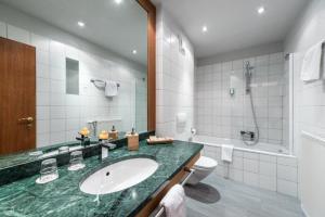 een badkamer met een wastafel, een toilet en een douche bij GORITSCHNIGGs Hotel - Self Check-In in Velden am Wörthersee +44 foto's