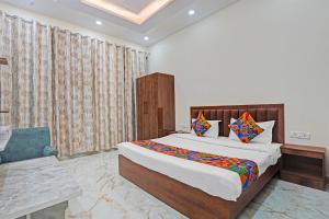 a bedroom with a large bed and a chair at FabHotel Winsome Inn in Noida
