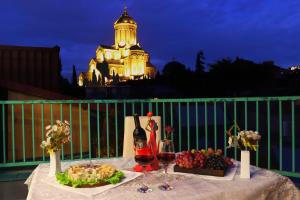una mesa con copas de vino y fruta en el balcón en Hotel Somi Inn, en Tiflis