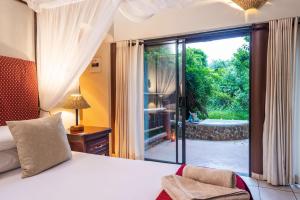 a bedroom with a bed and a view of a tub at Lodge Forest Suite in Hluhluwe