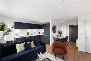 a living room with a blue couch and a table at Sleek & Stylish Apartment in the Best Area in Beckenham
