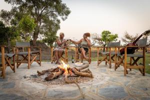 Un hombre y una mujer sentados alrededor de un fuego en Rain Tree Camp, en Chunga