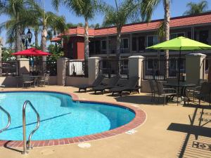a swimming pool with chairs and tables and umbrellas at Days Inn & Suites by Wyndham Anaheim At Disneyland Park in Anaheim
