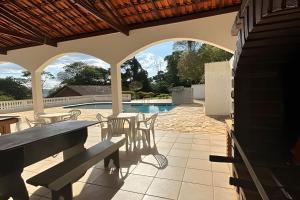 a patio with a table and chairs and a swimming pool at Casa Alpe de Itapeva in Itapeva
