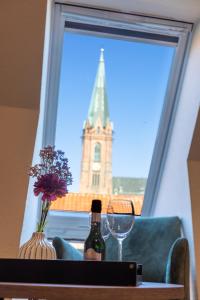 een fles wijn op een tafel met een raam met een toren bij Hotel Scheffler Lüneburg in Lüneburg