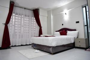 a bedroom with a large bed with red curtains at Araka Homes in Nakuru