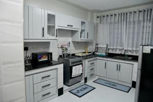 a kitchen with white cabinets and a stove top oven at Araka Homes in Nakuru +97 photos