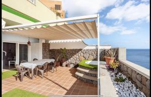 Un patio con mesa y sillas y el mar. en Apartamento con Vistas al mar y jacuzzi privado, en Santa Cruz de Tenerife