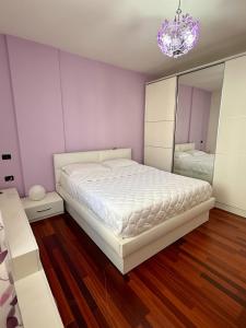 Un dormitorio con una cama blanca y un espejo. en Sea View Apartaments, en Durrës