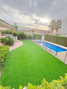 een tuin met groen gras en een zwembad bij Villa en la Playa I 5BR I 5 WC I Piscina Privada in Sueca