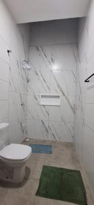 baño con aseo y alfombra verde en Prehenn Beach House com Piscina, en Itapoa