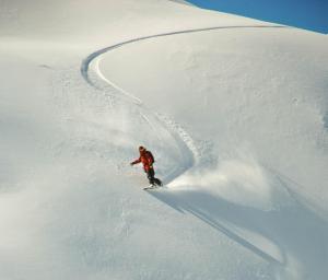 a man riding a snowboard down a snow covered slope at Vivelodge in Las Trancas