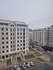 un grand bâtiment avec des voitures garées dans un parking dans l'établissement Уютная евродвушка возле Mega Silkway!, à Zhezdi