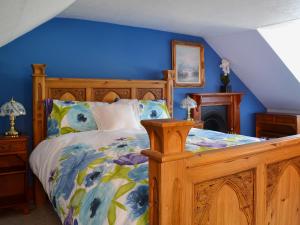 ein Schlafzimmer mit einem Holzbett mit einer blauen Wand in der Unterkunft Craigdarroch Cottage in Strathyre