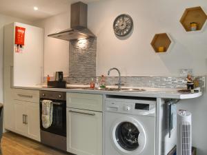 a kitchen with a washing machine and a clock on the wall at The Secret Luxury Apartment in New Romney