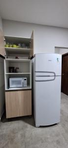 Una cocina con un refrigerador blanco y un microondas. en Prehenn Beach House com Piscina, en Itapoa