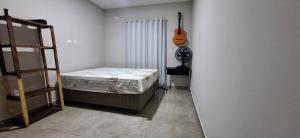 Un dormitorio con una cama y una guitarra en la pared en Prehenn Beach House com Piscina, en Itapoa 17 fotos más