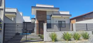 una casa con una valla delante en Prehenn Beach House com Piscina, en Itapoa