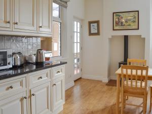 a kitchen with white cabinets and a table and chairs at Hillcrest in Pickering
