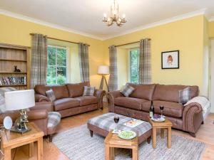 ein Wohnzimmer mit braunen Ledersofas und Tischen in der Unterkunft Grace's Cottage in Port of Menteith