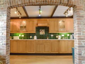 een keuken met houten kasten en een bakstenen muur bij The Granary in Colyford